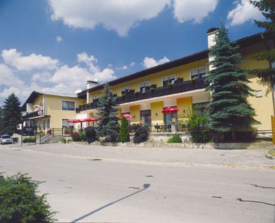 Gelbes Gebäude mit Café und Restaurant, umgeben von Bäumen, unter blauem Himmel.