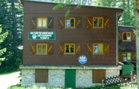 A three-storey building with wooden shutters and signs for Naturfreunde Ternitz.