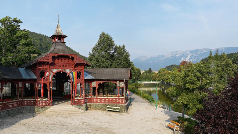 Ein roter Pavillon in Payerbach mit Bergen im Hintergrund.