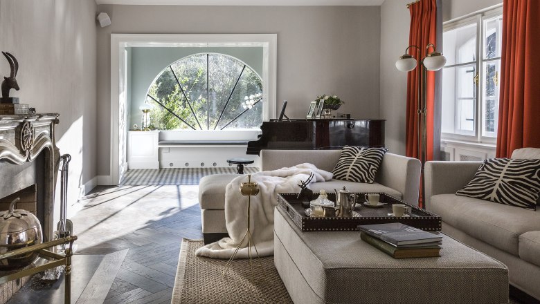 Elegantes Wohnzimmer mit Kamin, Klavier und gro&szlig;en Fenstern.