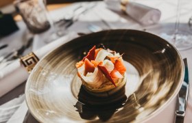 An artfully prepared dish on a brown plate in a restaurant.