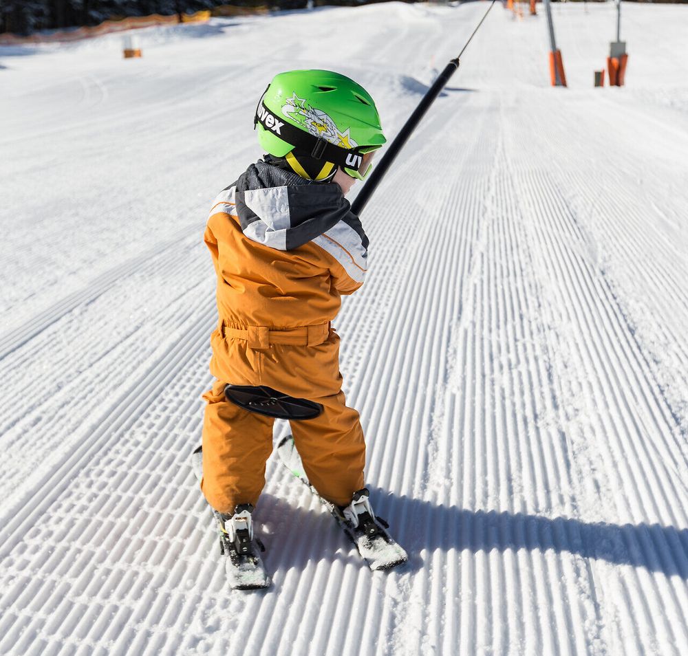 Ein kleiner Skifahrer genießt die frische Bergluft und die strahlende Sonne, während er sich auf den nächsten Schwung vorbereitet. Die perfekt präparierte Piste lädt zu aufregenden Abfahrten ein und verspricht unvergessliche Momente im Schnee.