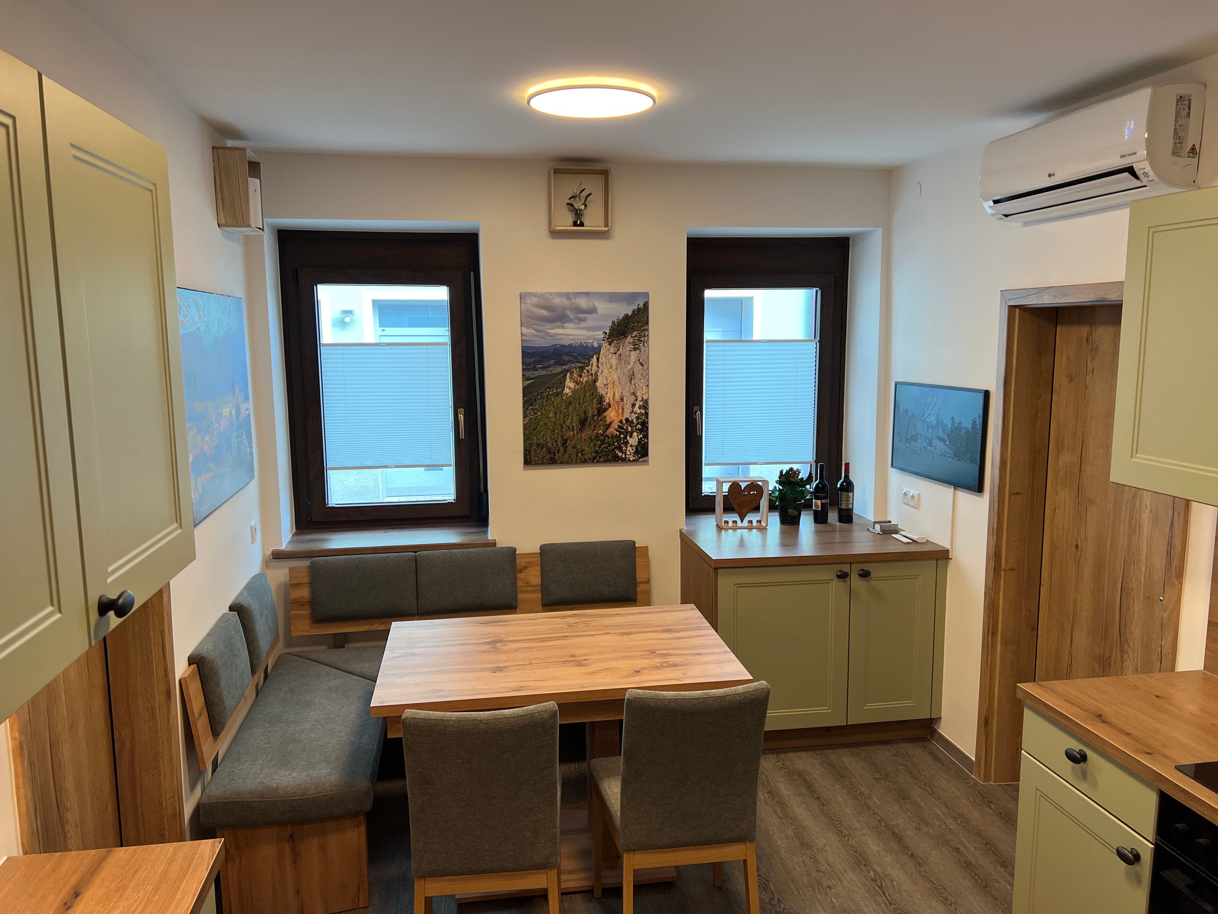 Moderne Küche mit Holzmöbeln, Esstisch und grünen Schränken.