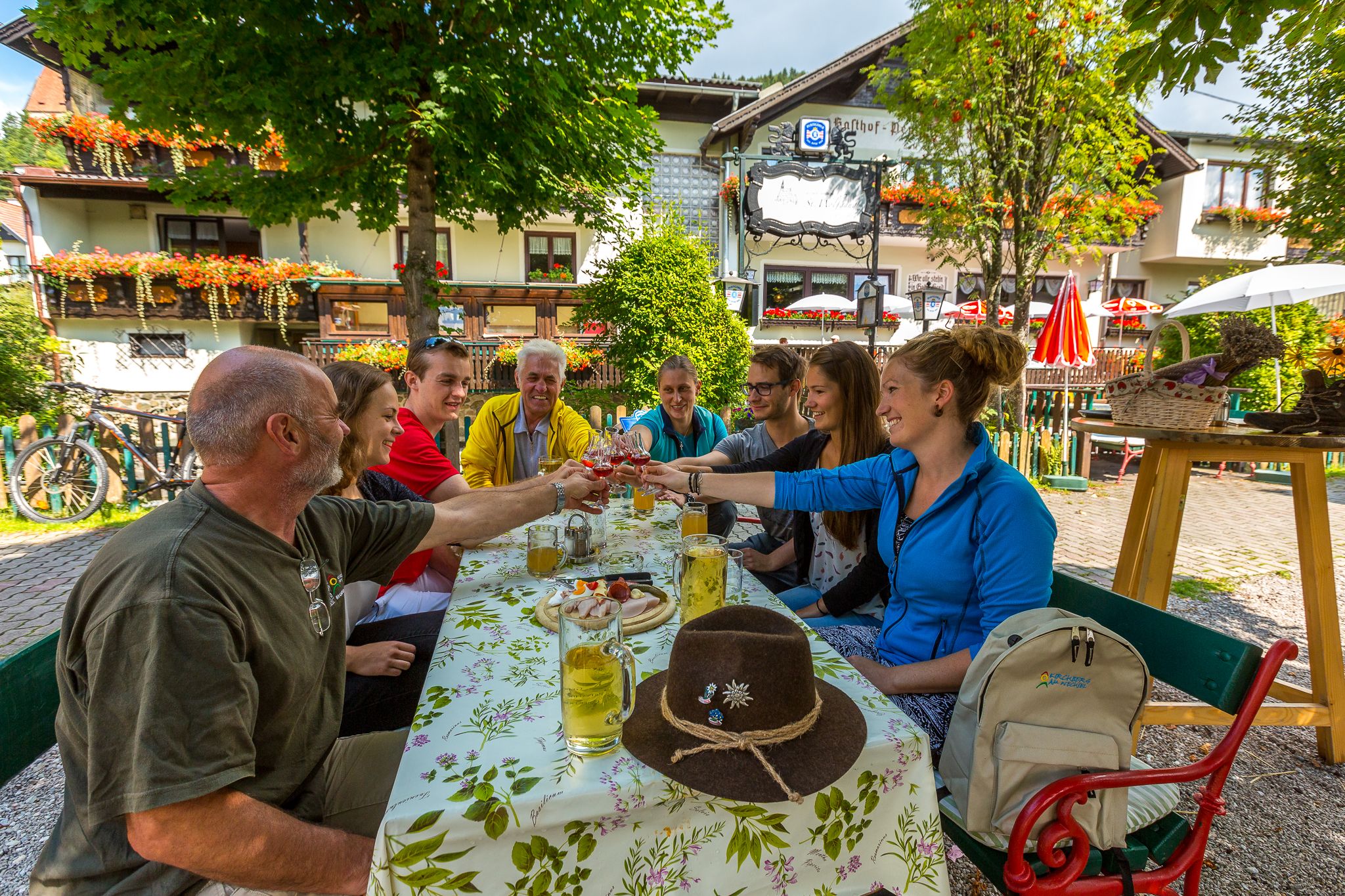 Gruppe von Menschen stößt in einem Gastgarten an.