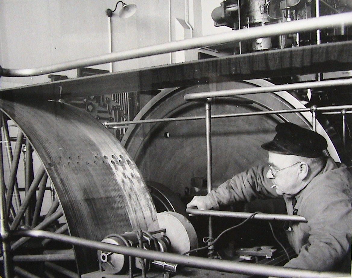 Historische Aufnahme in schwaz-weiß von einem Mann der an einer Maschine arbeitet
