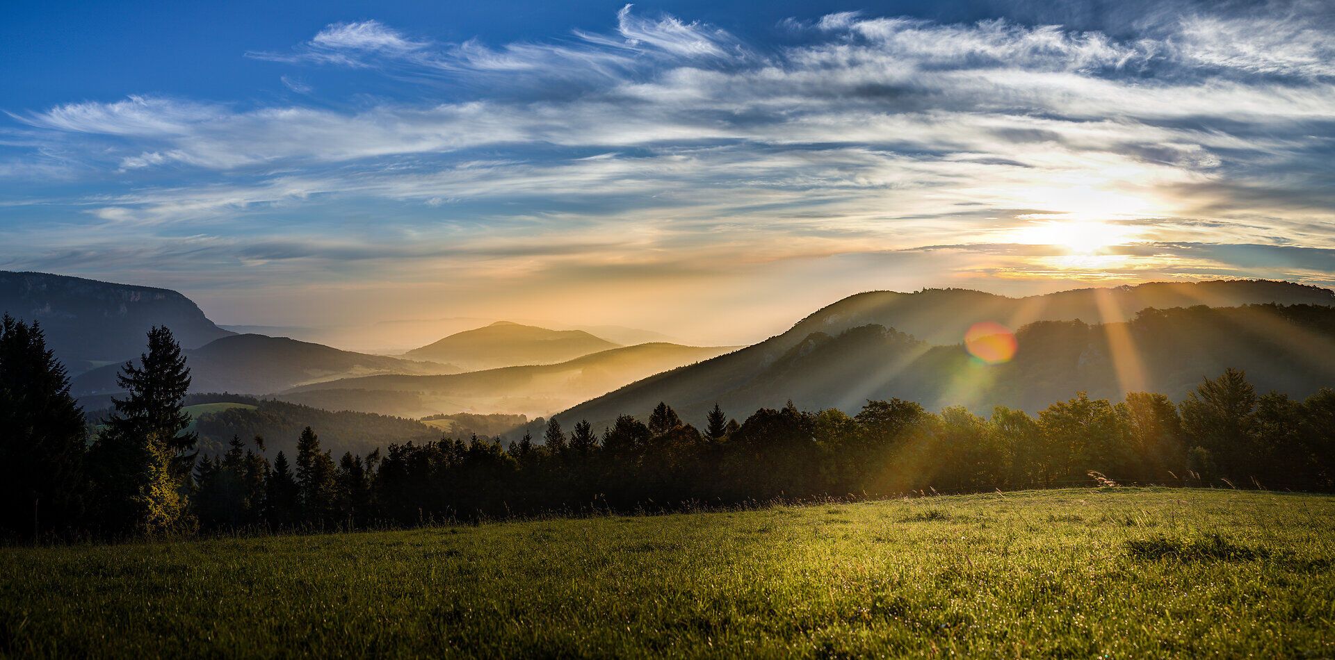 Der Sonnenaufgang taucht die majestätischen Berge in ein warmes, goldenes Licht und lässt die sanften Hügel im Nebel erstrahlen. Die frische Morgenluft und das sanfte Zwitschern der Vögel laden zu einem unvergesslichen Tag in der Natur ein.
