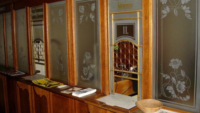 Historischer Postschalter mit Holzverkleidung und Glasfenstern.