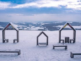 H&oacute;f&ouml;dte t&aacute;j, tetővel ell&aacute;tott h&aacute;zak form&aacute;j&uacute; fapadokkal a bakabui gyermek kalandp&aacute;ly&aacute;n Hutwischben.
