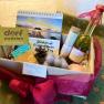 Ein Geschenkkorb mit verschiedenen Wellness-Produkten, darunter ein Kalender, eine Flasche &Ouml;l und handgemachte Seifen.