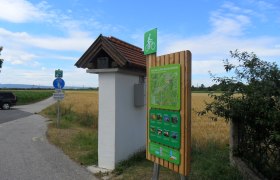 Bicycle starting point sign in Katzelsdorf with signpost and landscape in the background.