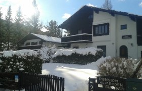 Verschneites Haus mit Schild 'Pension Almboden' im Vordergrund.