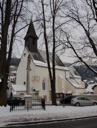 Eine Kirche im Winter mit schneebedecktem Boden und kahlen Bäumen.