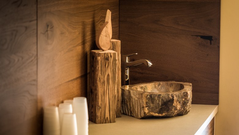 Rustic wooden washbasin with tap and wooden decor.