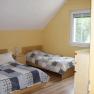 Two single beds in a yellow-painted bedroom with sloping ceiling and window.