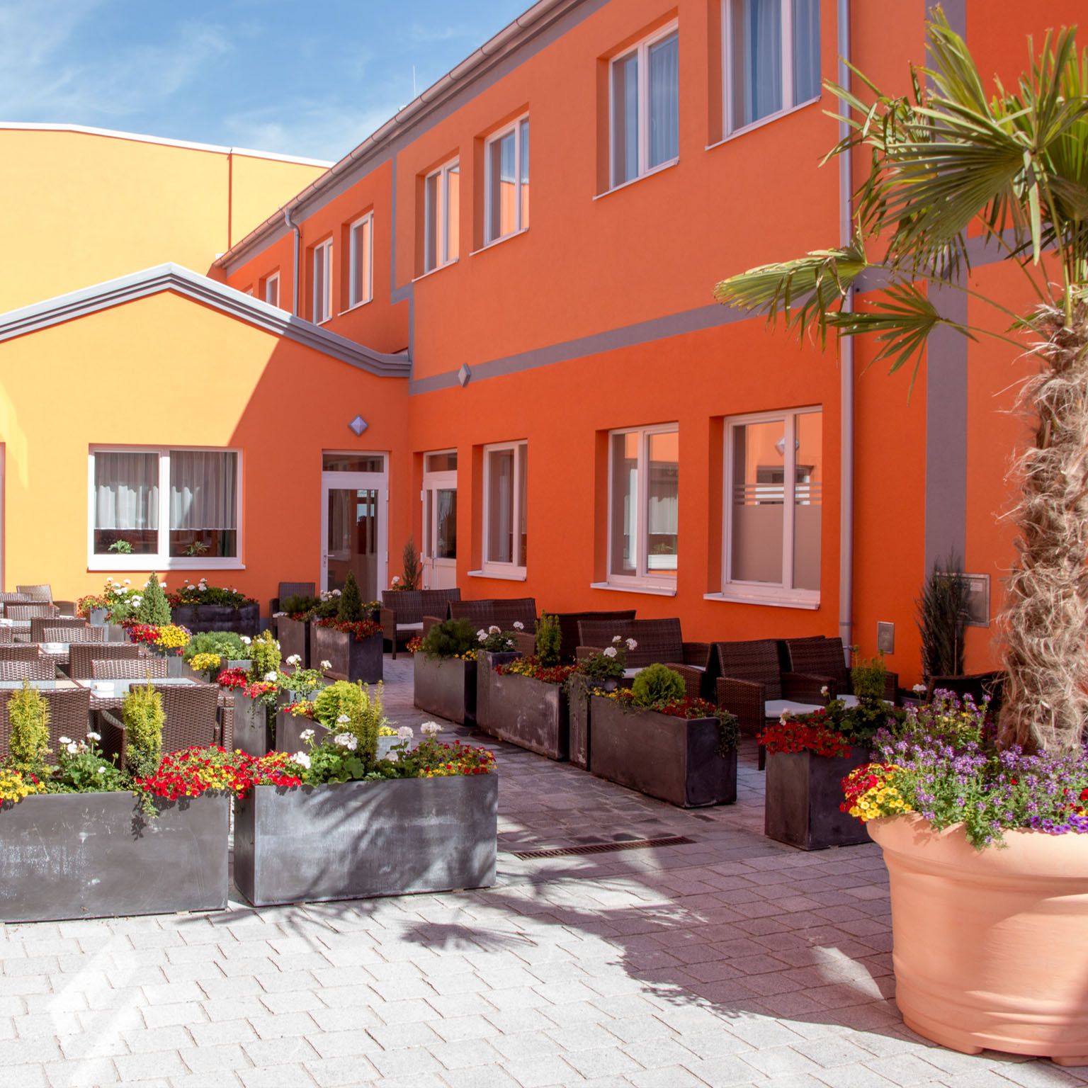 Außenansicht des Hotel Winrooms in Wiener Neustadt mit orangefarbener Fassade und Uhr.