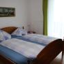 Double room with wooden bed, blue and white checkered bed linen, picture on the wall and green curtain.