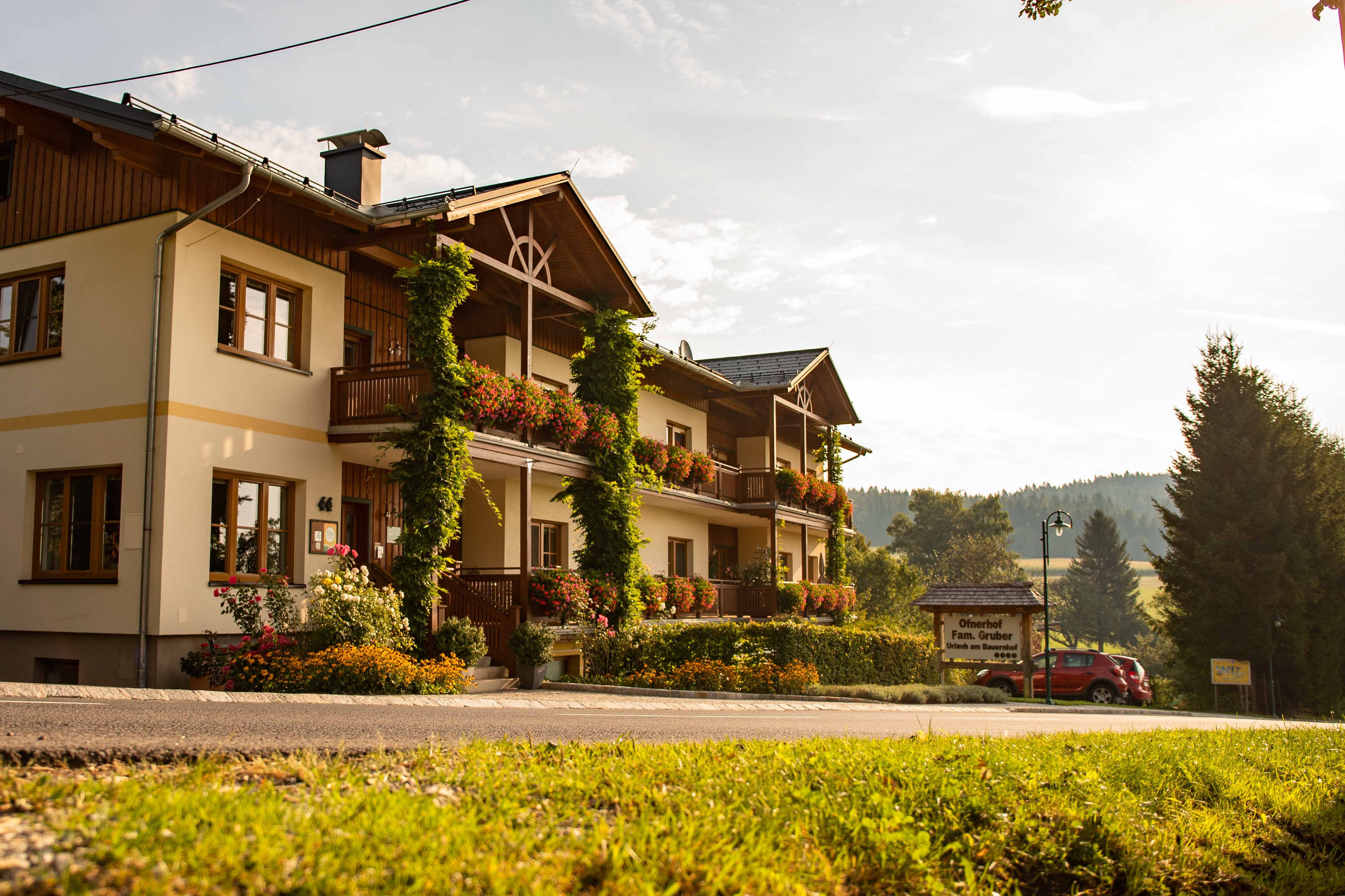 Ein traditionelles Gasthaus mit Blumen geschmückten Balkonen in ländlicher Umgebung bei Sonnenuntergang.