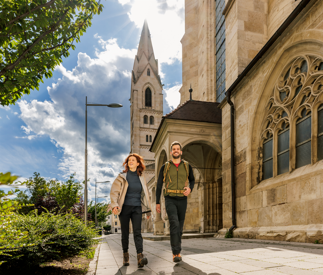 Pärchen, welches am Dom Wiener Neustadt vorbeiwandert