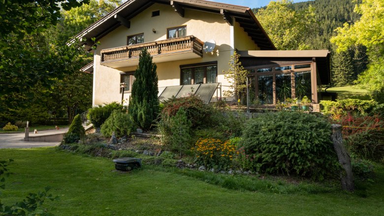 Ferienhaus Schlager, © Claudia Schlager Ein zweistöckiges Ferienhaus mit Balkon und Garten, umgeben von Bäumen und Wiese.