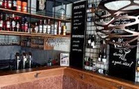 Innenansicht eines modernen Restaurants mit Weinregalen und Tafeln an den Wänden.