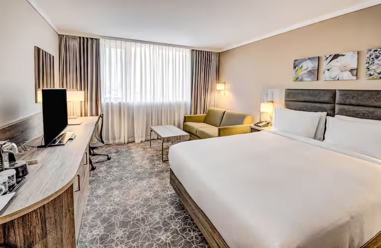 Helles, modernes Schlafzimmer mit Schreibtisch, Fernseher und Doppelbett