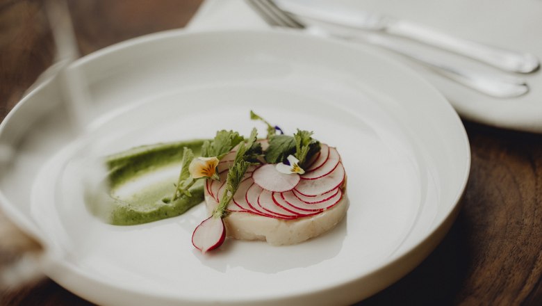 A dish with char, radishes and wasabi cream, decorated with edible flowers.