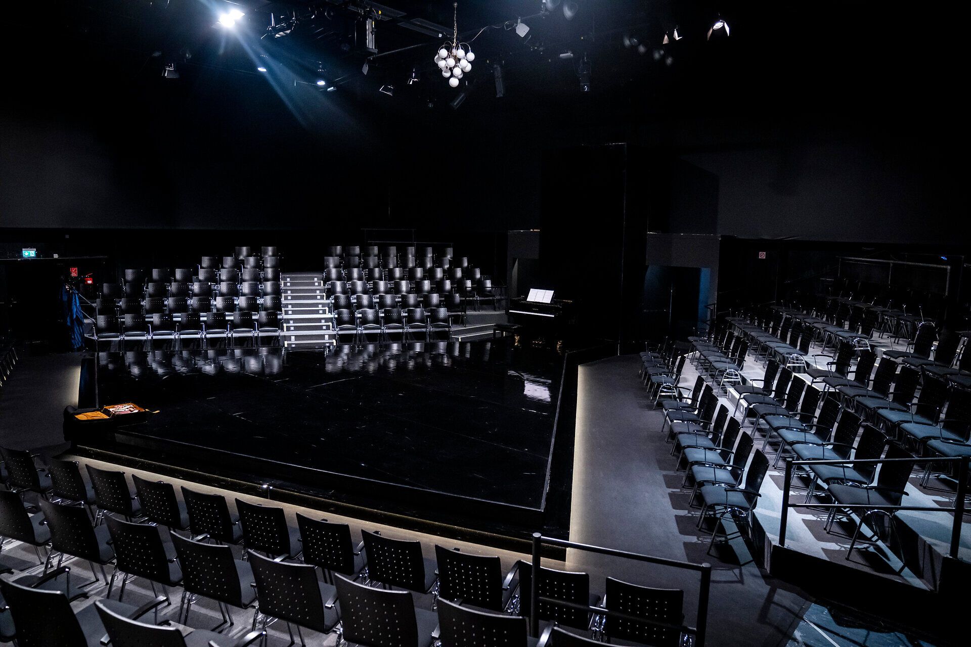 Ein stilvolles Theaterambiente erwartet die Besucher, die sich auf ein unvergessliches Erlebnis freuen. Die schlichten, eleganten Sitzreihen und die sanfte Beleuchtung schaffen eine einladende Atmosphäre, die die Vorfreude auf die bevorstehenden Aufführungen steigert.