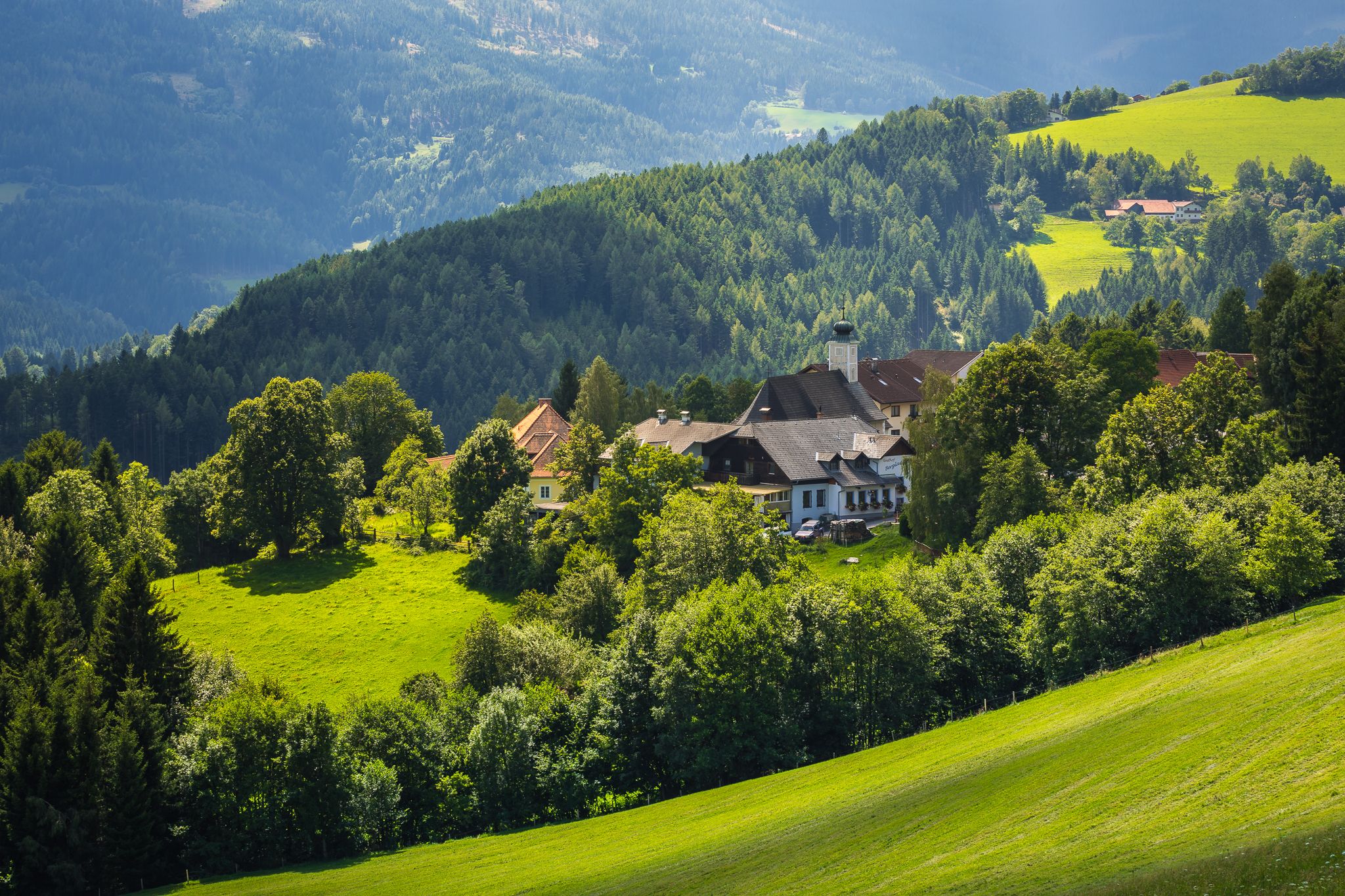 Ländliche Landschaft mit Häusern und grünen Hügeln.