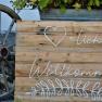 Wooden sign with the inscription 'Welcome' and a heart symbol, next to it an old wagon wheel.