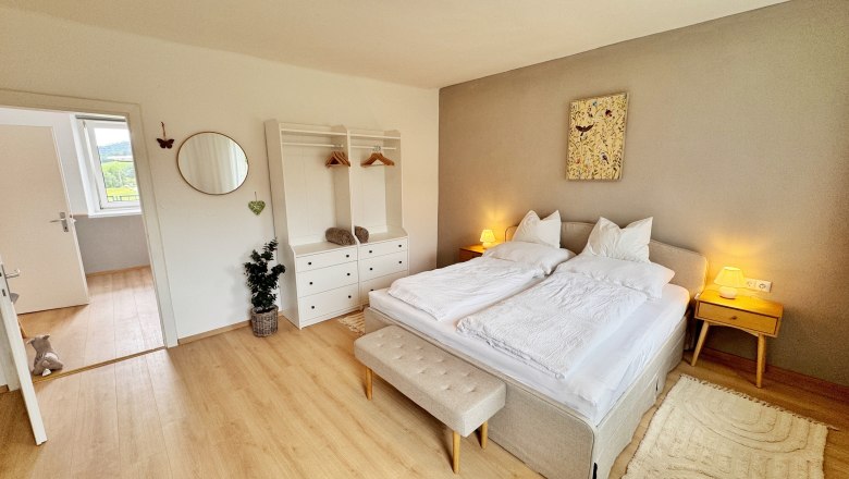 Ein gemütliches Schlafzimmer mit Doppelbett, Nachttischen, Kleiderschrank und Dekoration.