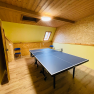 A playroom with table tennis table, yellow walls and wooden ceiling.