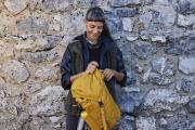 Frau mit gelbem Rucksack vor einer Mauer