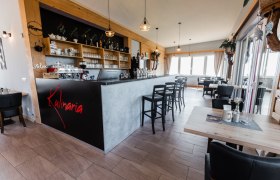 Innenansicht eines modernen Restaurants mit Bar und Sitzbereich.