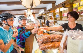 Two cyclists in a caf&eacute; being served by a sales clerk.
