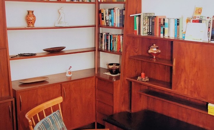 Gemütliche Leseecke mit Holzregalen, Büchern und einem Sessel.