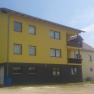 Yellow building with several windows and balconies, blue sky in the background.