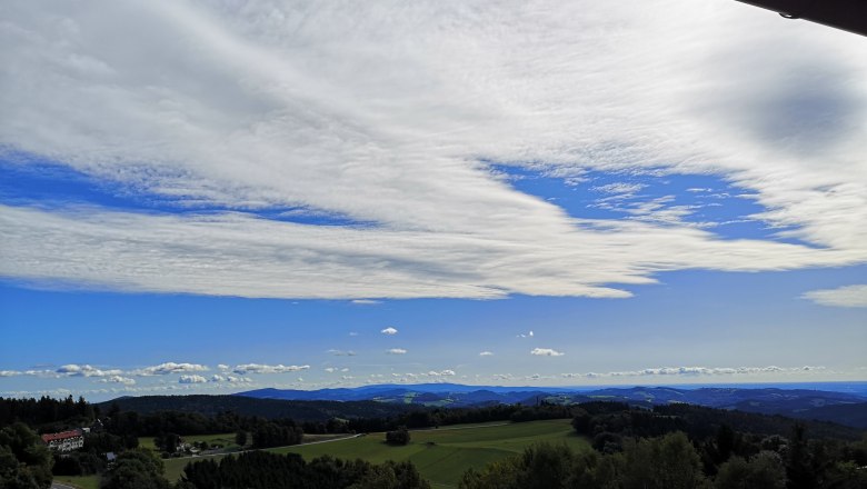 Landscape with hills, forests and a wide sky with clouds.