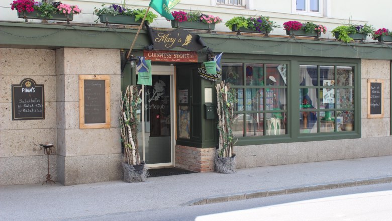 Entrance to a pub with a green façade and flower boxes.
