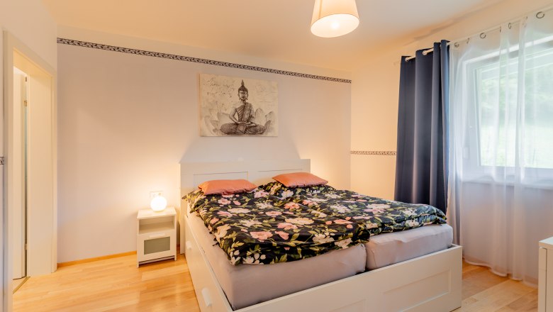 Gemütliches Schlafzimmer mit Doppelbett, Nachttischlampe und Buddha-Bild an der Wand.