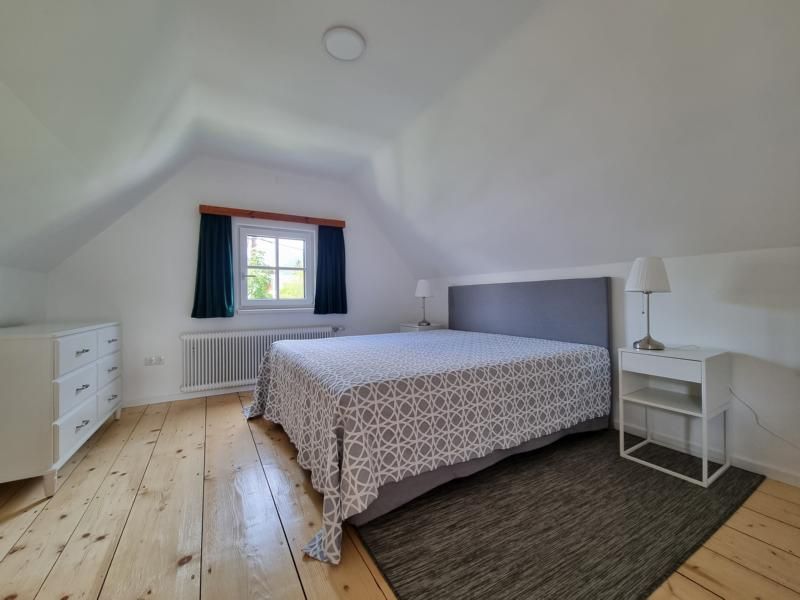 Schlafzimmer mit Doppelbett, Nachttischen und Kommode.