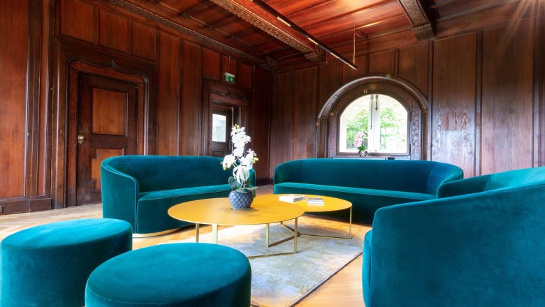Elegant living room with green sofas and wooden walls.