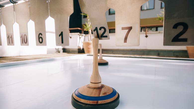 Curling on a smooth surface in front of numbered targets.