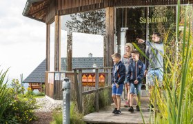 Familie auf Holzweg vor einem Gebäude mit der Aufschrift 'Salaerium'.