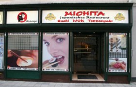 Eingang des Michita japanischen Restaurants mit gro&szlig;en Fenstern und Werbebildern.