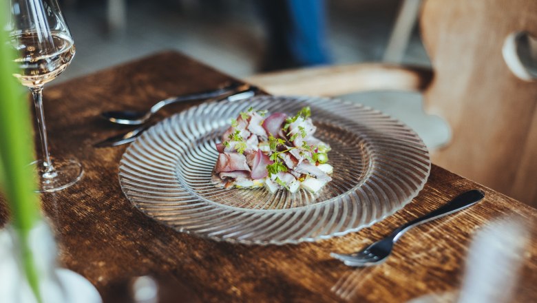A plate of roast beef and asparagus salad on a wooden table, with a glass of white wine next to it.