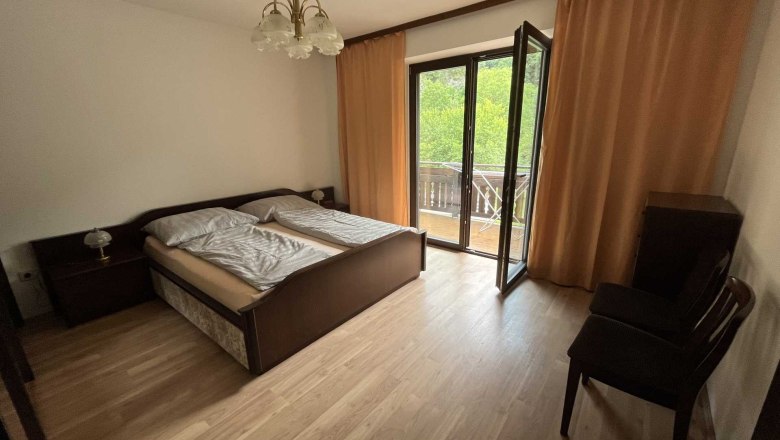 Bedroom with double bed, balcony and curtains.