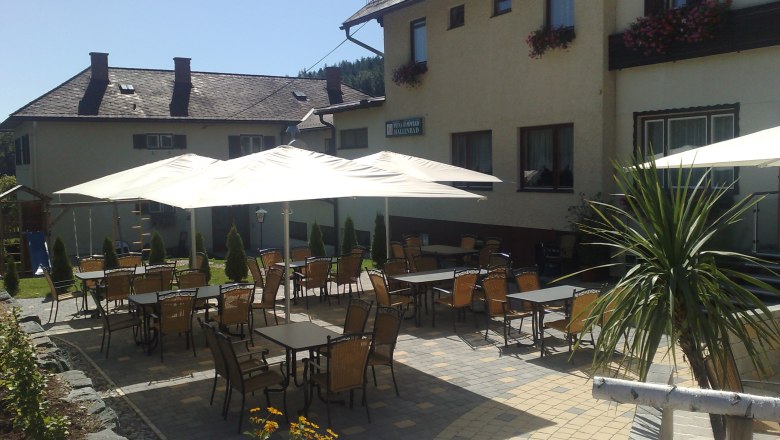 Gasthof-Pension Seelhofer, © Gasthof-Pension Seelhofer Außenbereich einer Pension mit Tischen, Stühlen und Sonnenschirmen.