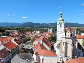 Ausblick auf Neunkirchen mit H&auml;usern, Kirche und Bergen im HIntergrund.