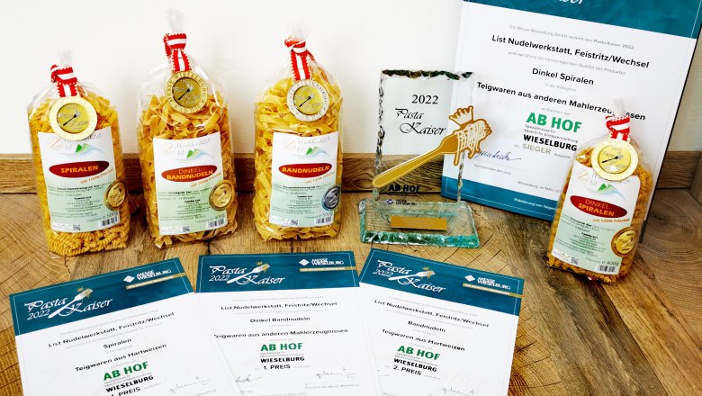 Verschiedene Nudelpackungen und Auszeichnungen auf einem Holzboden.