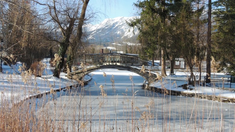 Verschneite Landschaft mit gefrorenem Fluss und Brücke in Reichenau.